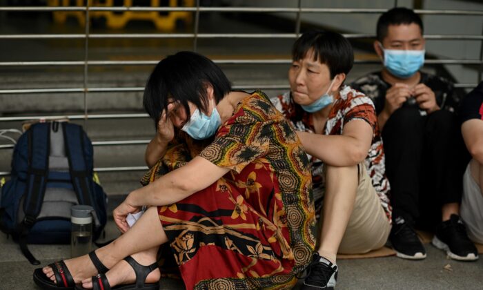 A woman cries as she and other people gather at the Evergrande headquarters in Shenzhen, China on Sept. 16, 2021, as the Chinese property giant stated that it's facing "unprecedented difficulties," but denied rumors that it's about to go under. (Noel Celis/AFP via Getty Images)