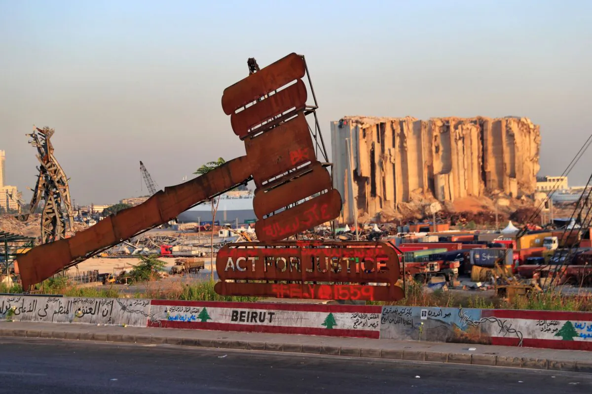 A monument that represents justice stands in front of towering grain silos that were gutted in the massive August 2020 explosion at the port that killed more than 200 people and wounded over 6,000, in Beirut, Lebanon on Aug. 4, 2021. (Hussein Malla/AP Photo File)