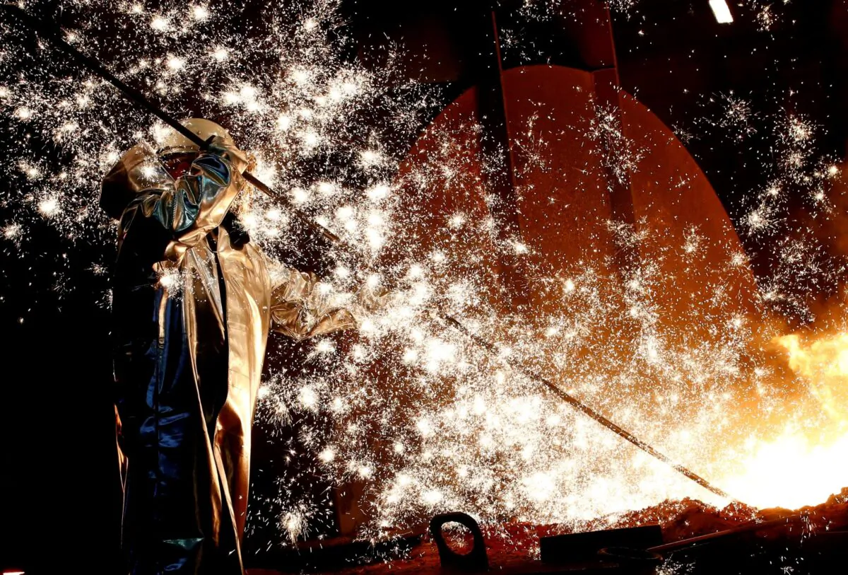 A steel worker of Germany's industrial conglomerate ThyssenKrupp AG stands a mid of emitting sparks of raw iron from a blast furnace at Germany's largest steel factory in Duisburg, Germany. (Wolfgang Rattay/Reuters)