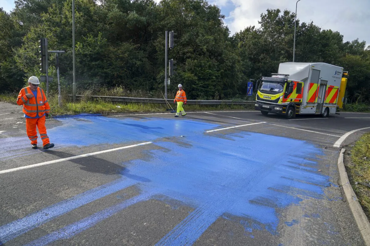 Highways England workers on the exit slip road of the M25 motorway near Leatherhead after protestors blocked the road and left paint on it, on Sept. 17, 2021. (PA)