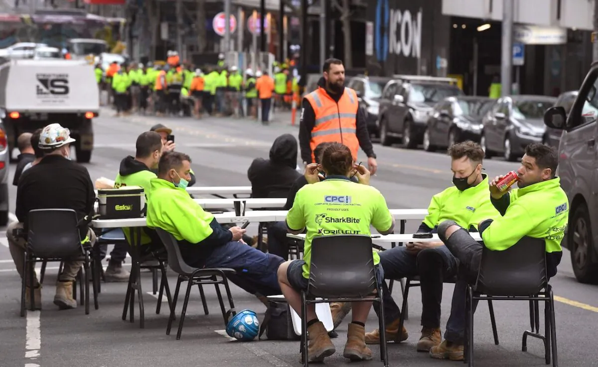 Construction workers take their lunch break on a busy street in Melbourne, to protest the closing of their onsite tea rooms by the state government, on Sept. 17, 2021. (William West/AFP via Getty Images)