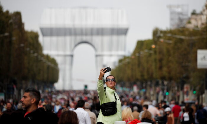 A woman takes a selfie near the Arc de Triomphe monument, fully wrapped as part of an art installation entitled "L'Arc de Triomphe, Wrapped" conceived by the late artists Christo and Jeanne-Claude, on the Champs Elysees avenue during a car-free sunday in Paris, France, on Sept.19, 2021. (Benoit Tessier/Reuters)