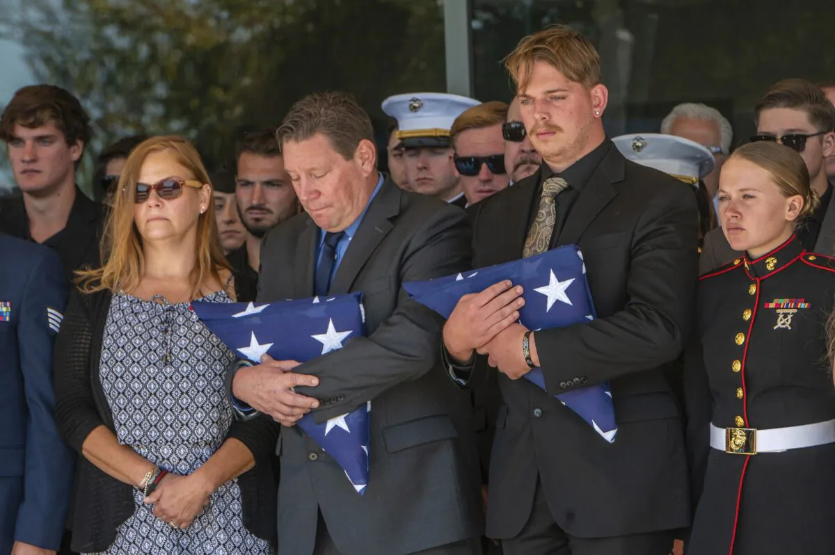 After the service for fallen Marine Sgt. Nicole Gee, her father Richard Herrera, center, and husband Jarod Gee, right, hold U.S. flags as her casket is moved to the hearse at Bayside Church Adventure Campus in Roseville, Calif., on Sept. 18, 2021. (Renee C. Byer/The Sacramento Bee via AP)
