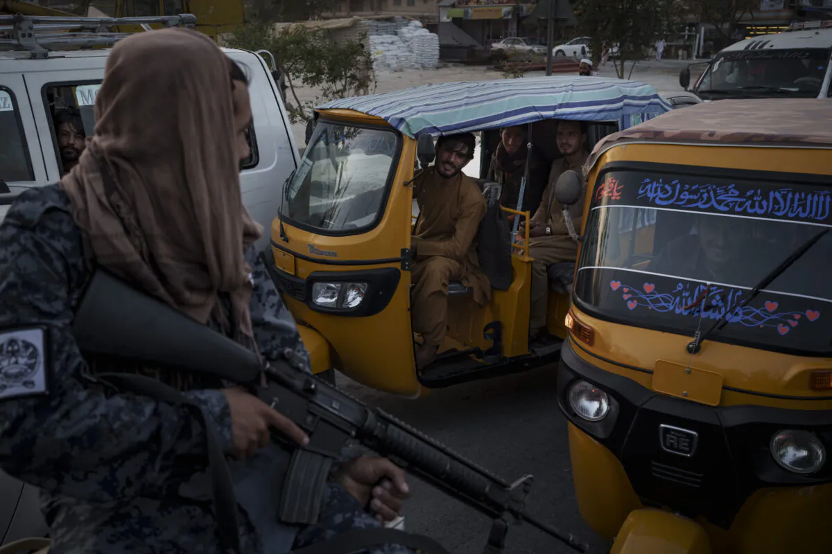 Afghan drivers and passengers stuck in a traffic jam look at Taliban fighters riding in the back of a pickup truck in Kabul, Afghanistan, on Sept. 20, 2021. (Felipe Dana/AP Photo)