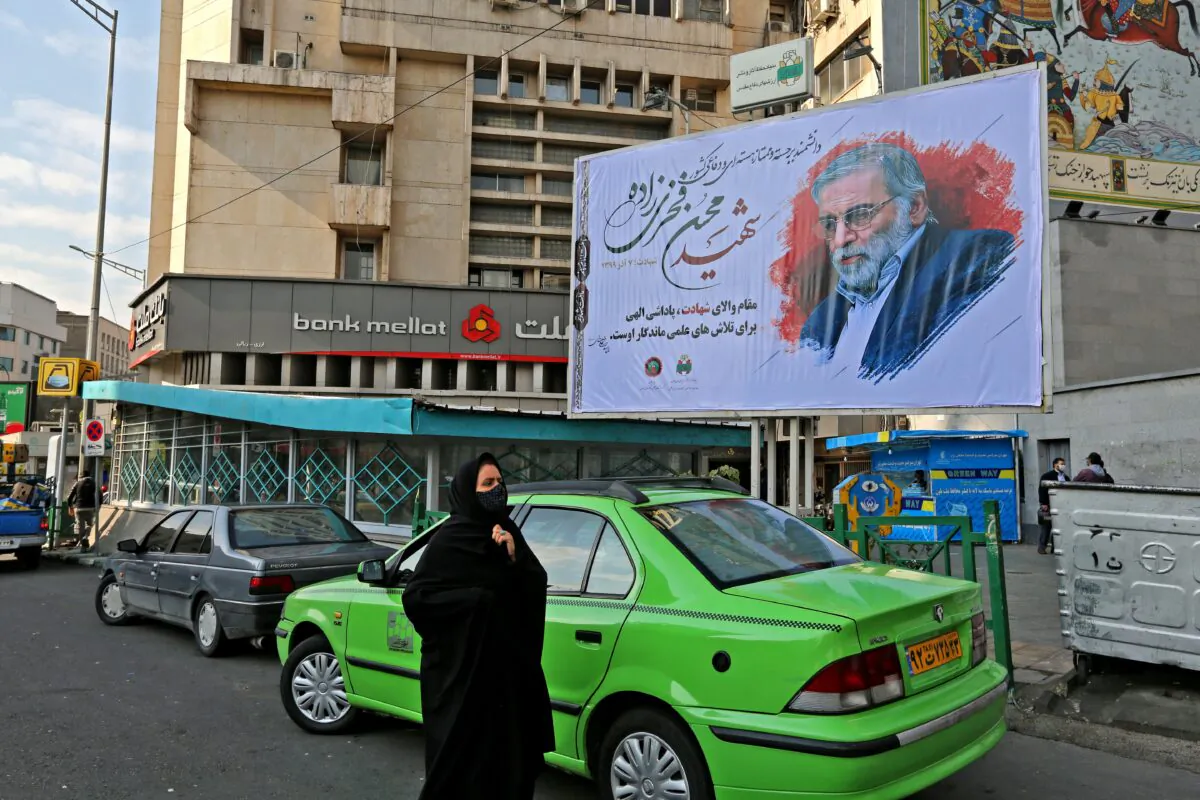 A woman walks by a billboard honoring slain nuclear scientist Mohsen Fakhrizadeh in the Iranian capital Tehran, on Nov. 30, 2020. (Atta Kenare/AFP via Getty Images)