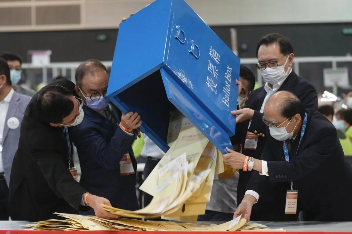 Erick Tsang (2nd from L) Secretary for Constitutional and Mainland Affairs Bureau, helps officials in pouring out ballots from a box at a counting center
in Hong Kong on Sept. 19, 2021. (Vincent Yu/AP Photo)