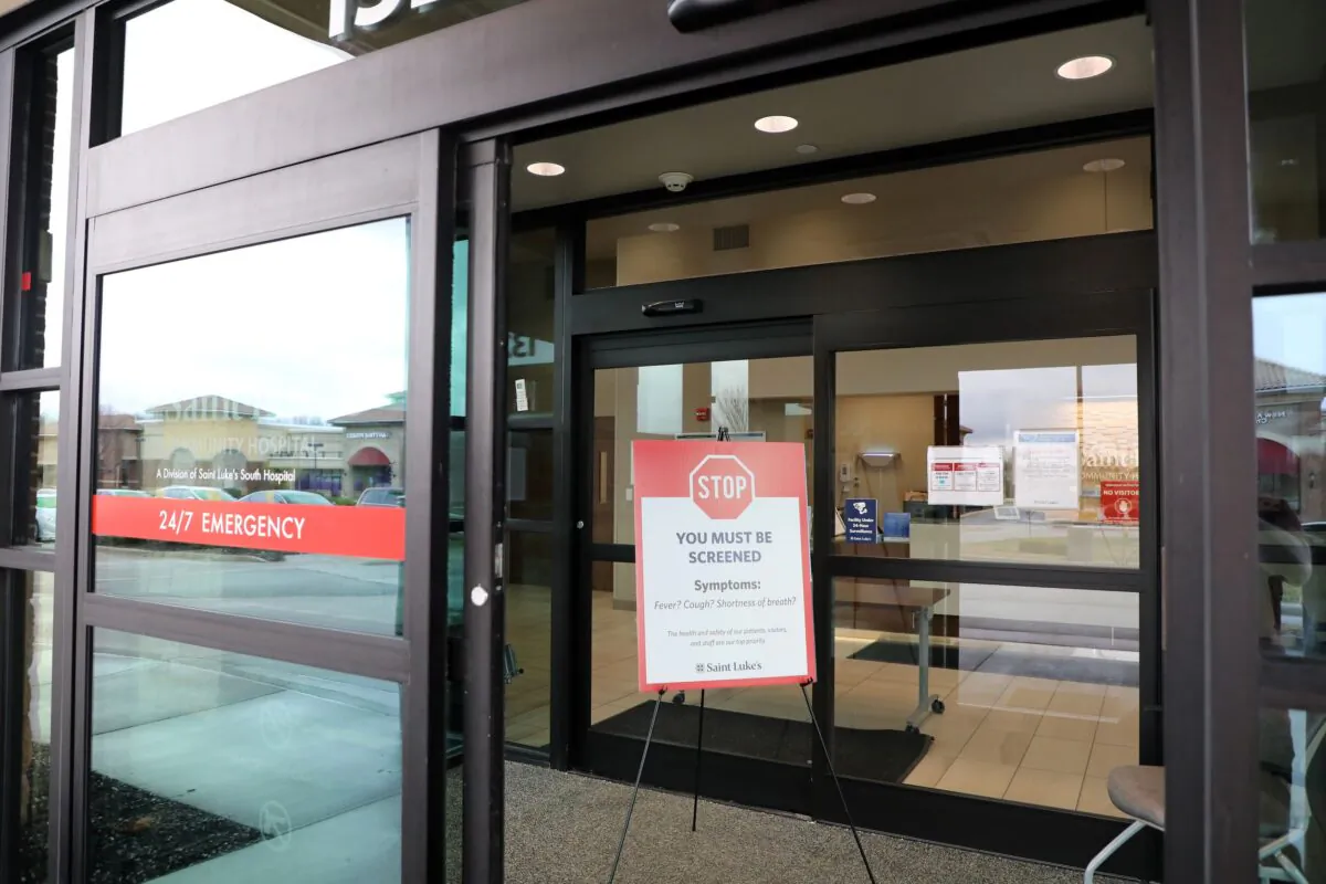 A sign informing patients that they must be screened before admittance at an emergency room is seen at a health clinic in Kansas City, Kans., on March 26, 2020. (Jamie Squire/Getty Images)