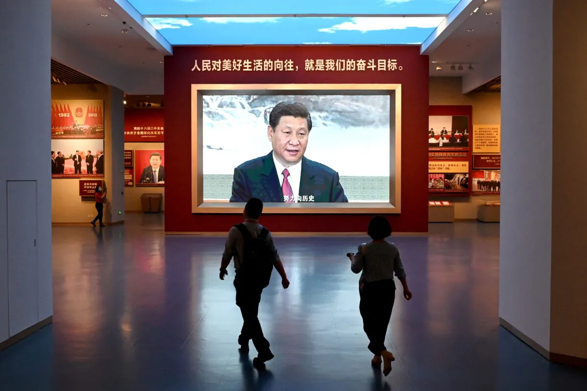 Journalists walk past a screen showing video footage of Chinese leader Xi Jinping, during a visit to the Museum of the Communist Party of China, near the Birds Nest national stadium in Beijing on June 25, 2021. (Noel Celis/AFP via Getty Images)
