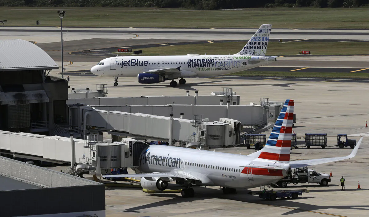 A JetBlue Airbus A320 taxis to a gate after landing, as an American Airlines jet is seen parked at its gate at Tampa International Airport in Tampa, Fla., on Oct. 26, 2016. (Chris O'Meara/AP Photo)