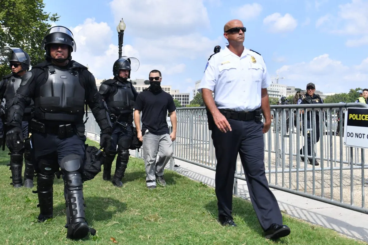 A man later identified as a Customs and Border Protection Officer (C) is escorted by U.S. Capitol Police officers away from a rally in Washington on Sept. 18, 2021. (Eric Baradat/AFP via Getty Images)