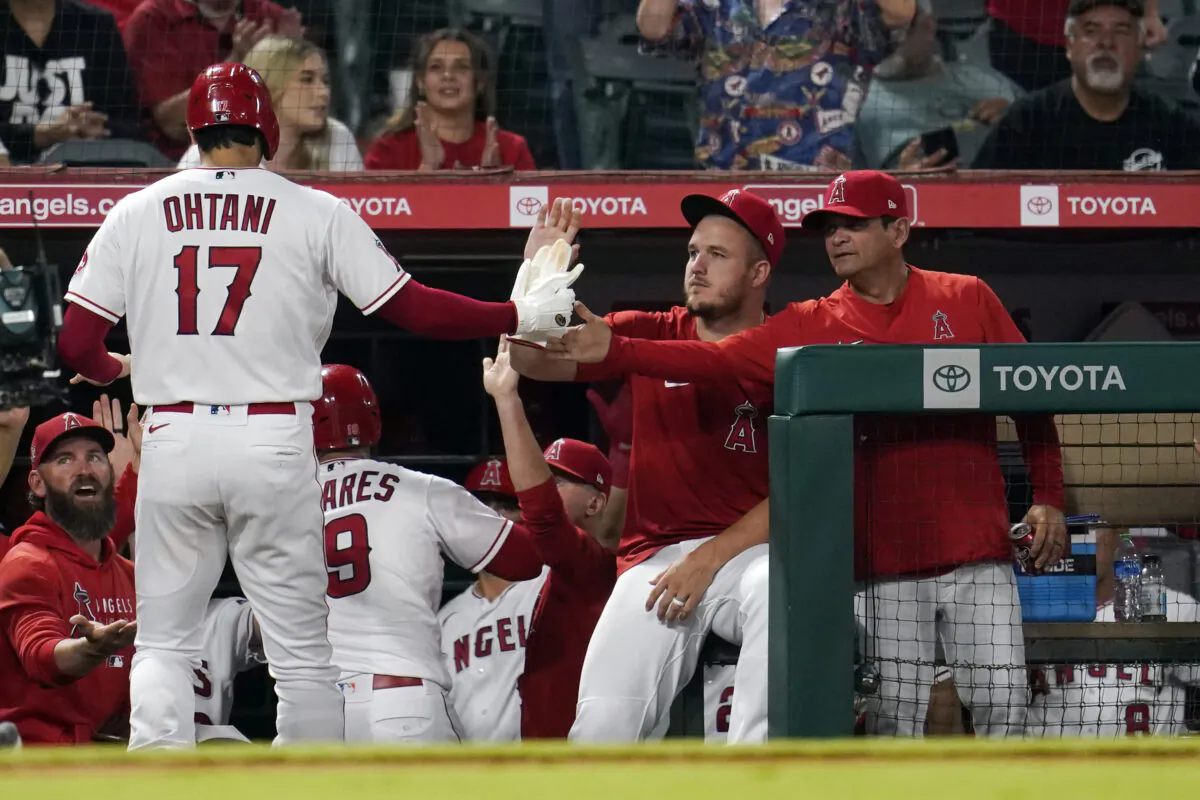 Los Angeles Angels' Shohei Ohtani (17) is met in the dugout by Mike Trout, center, and bench coach Mike Gallego, right, during the sixth inning of a baseball game against the Houston Astros in Anaheim, Calif., on Sept. 21, 2021. (AP Photo/Marcio Jose Sanchez)