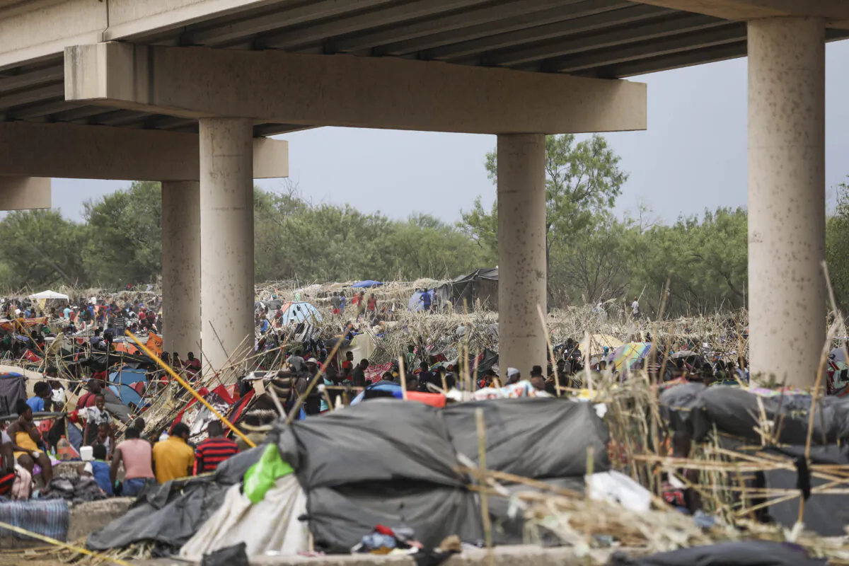 Thousands of illegal immigrants, mostly Haitians, live in a primitive, makeshift camp under the international bridge that spans the Rio Grande between the United States and Mexico while waiting to be detained and processed by Border Patrol, in Del Rio, Texas, on Sept. 21, 2021. (Charlotte Cuthbertson/The Epoch Times)