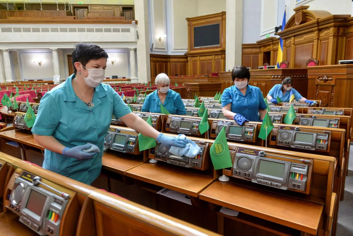 Employees use disinfectant while cleaning the Ukrainian lawmakers' working places in the session hall of parliament in Kiev, Ukraine on March 19, 2020. (Stringer/Reuters)
