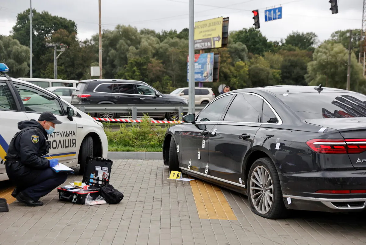 An investigator examines bullet holes in a car of Serhiy Shefir, Ukrainian President Volodymyr Zelensky's principal aide, following an assault outside of Kyiv, Ukraine, on Sept. 22, 2021. (Serhii Nuzhnenko/Reuters)