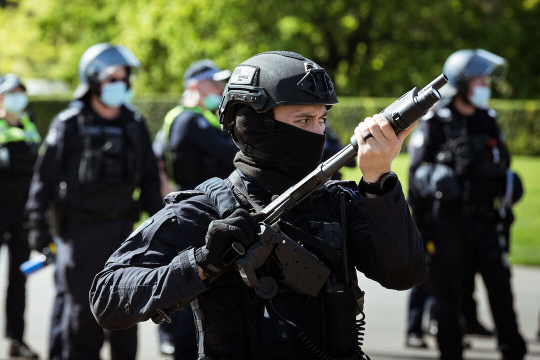 A riot police officer wields a weapon looking onwards at COVID-19 lockdown protesters near the Shrine of Remembrance, in Melbourne, Australia, on Sept. 22, 2021. (Darrian Traynor/Getty Images)