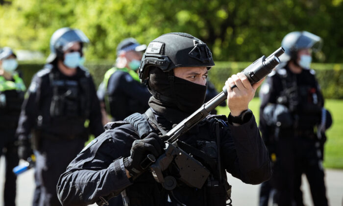 A riot police officer wields a weapon looking onwards at protesters near the Shrine of Remembrance, in Melbourne, Australia, on Sept. 22, 2021. (Darrian Traynor/Getty Images)