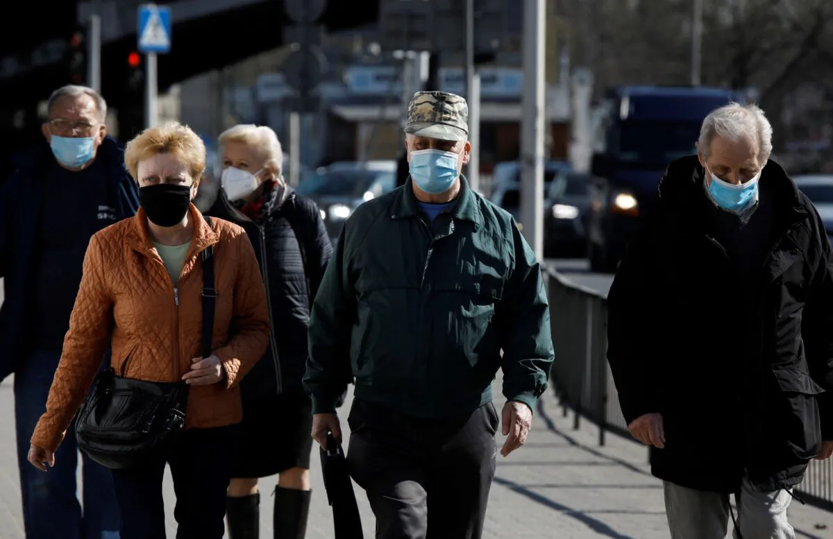 People wearing protective masks walk in Warsaw, Poland, on April 2, 2021. (Kacper Pempel/Reuters)