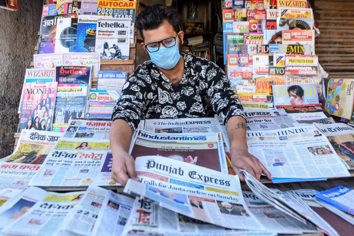A vendor wearing a mask displays newspapers at his stall in Amritsar, a city in India, on March 20, 2020. (Narinder Nanu/AFP via Getty Images)