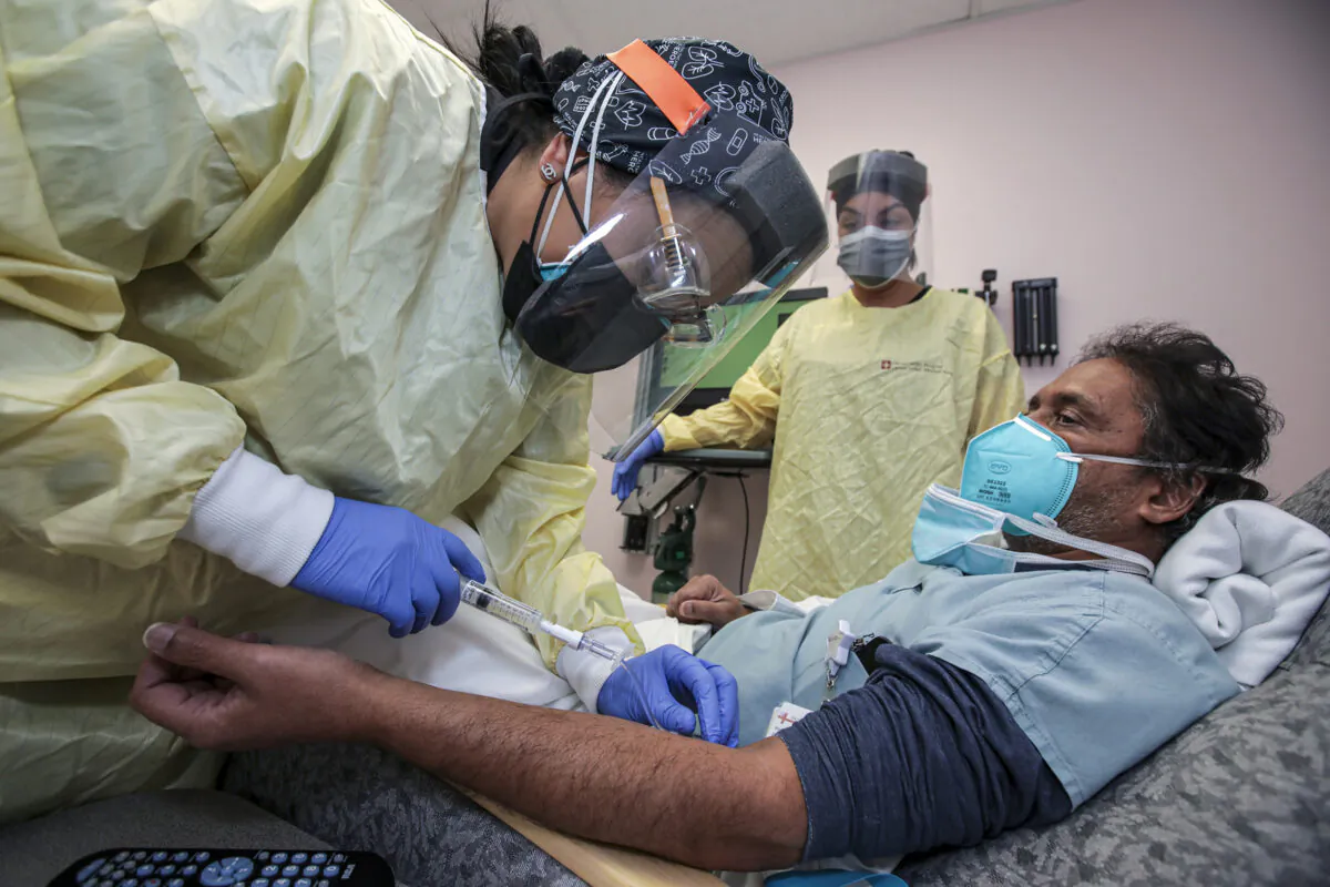 Nurse Salina Padilla (L) prepares Dr. Prabakar Tummala for Bamlanivimab, monoclonal antibody infusion at Desert Valley Hospital in Victorville, Calif., on Dec. 17, 2020. (Irfan Khan/Los Angeles Times/TNS)