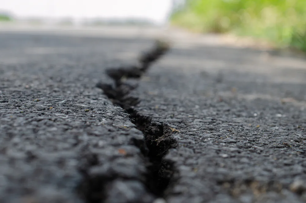 It's important to keep cracks in asphalt as filled and closed as possible; if water seeps in, it will make the base unstable. (NARENTHORN/Shutterstock)