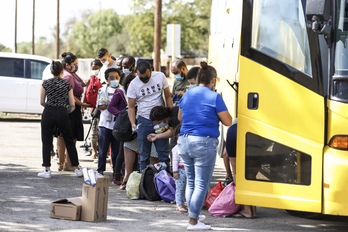 Haitians and others who crossed the U.S. border illegally are seen boarding a bus after being released by federal authorities, in Del Rio, Texas, on Sept. 22, 2021. (Charlotte Cuthbertson/The Epoch Times)