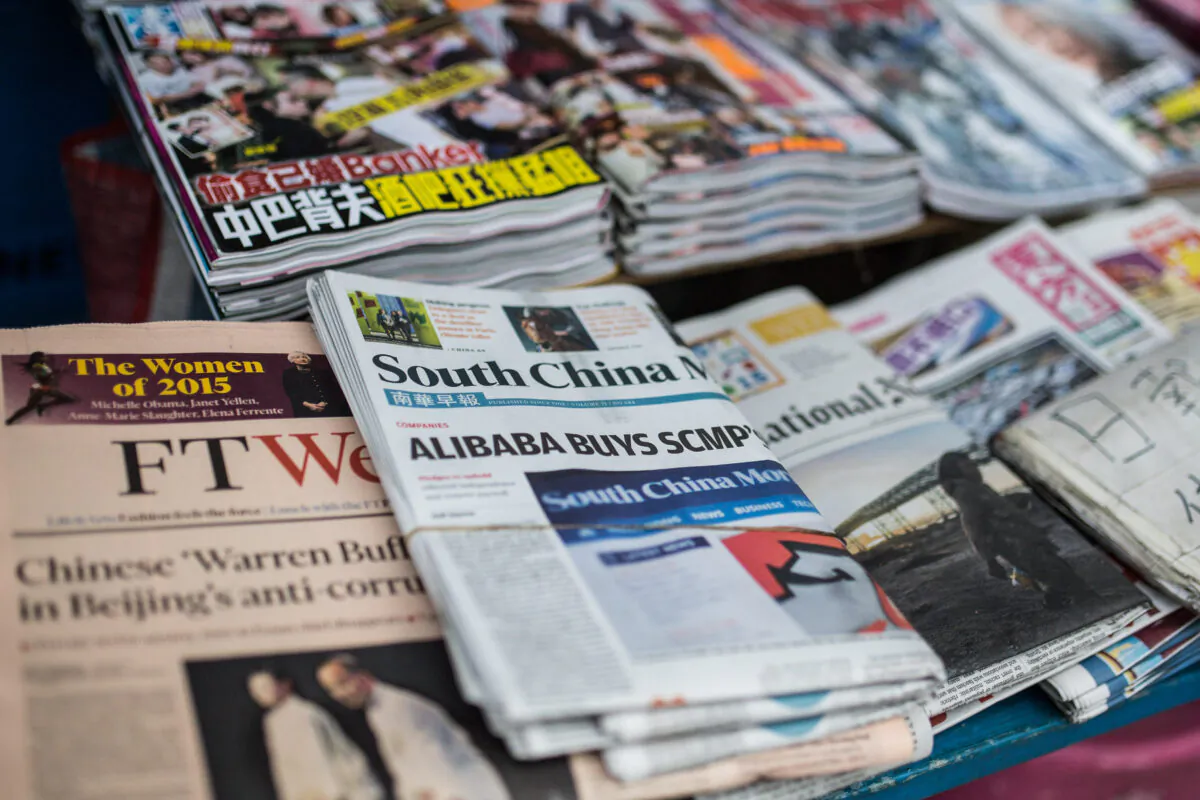 A copy (C) of the South China Morning Post is displayed at a newsstand in Hong Kong on Dec. 12, 2015, following its acquisition by Chinese Internet giant Alibaba of the English-language newspaper. (Anthony Wallace/AFP via Getty Images)