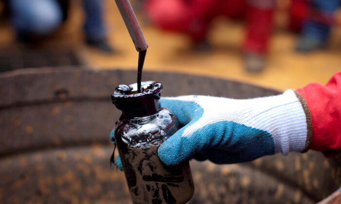 A worker collects a crude oil sample at an oil well operated by Venezuela's state oil company PDVSA in Morichal, Venezuela, on July 28, 2011. (Carlos Garcia Rawlins/Reuters)