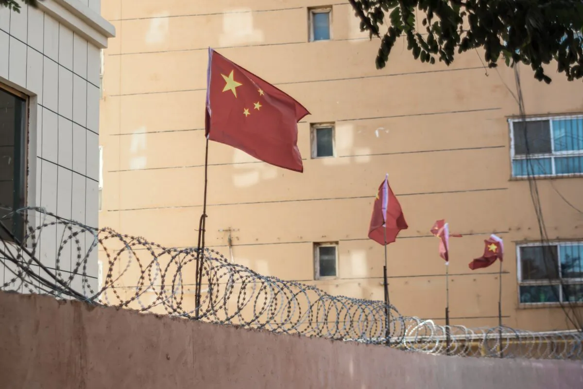 Chinese flags on barbed wire wall in Kashgar, Xinjiang, China. (Jonathan Densford/Adobe Stock)