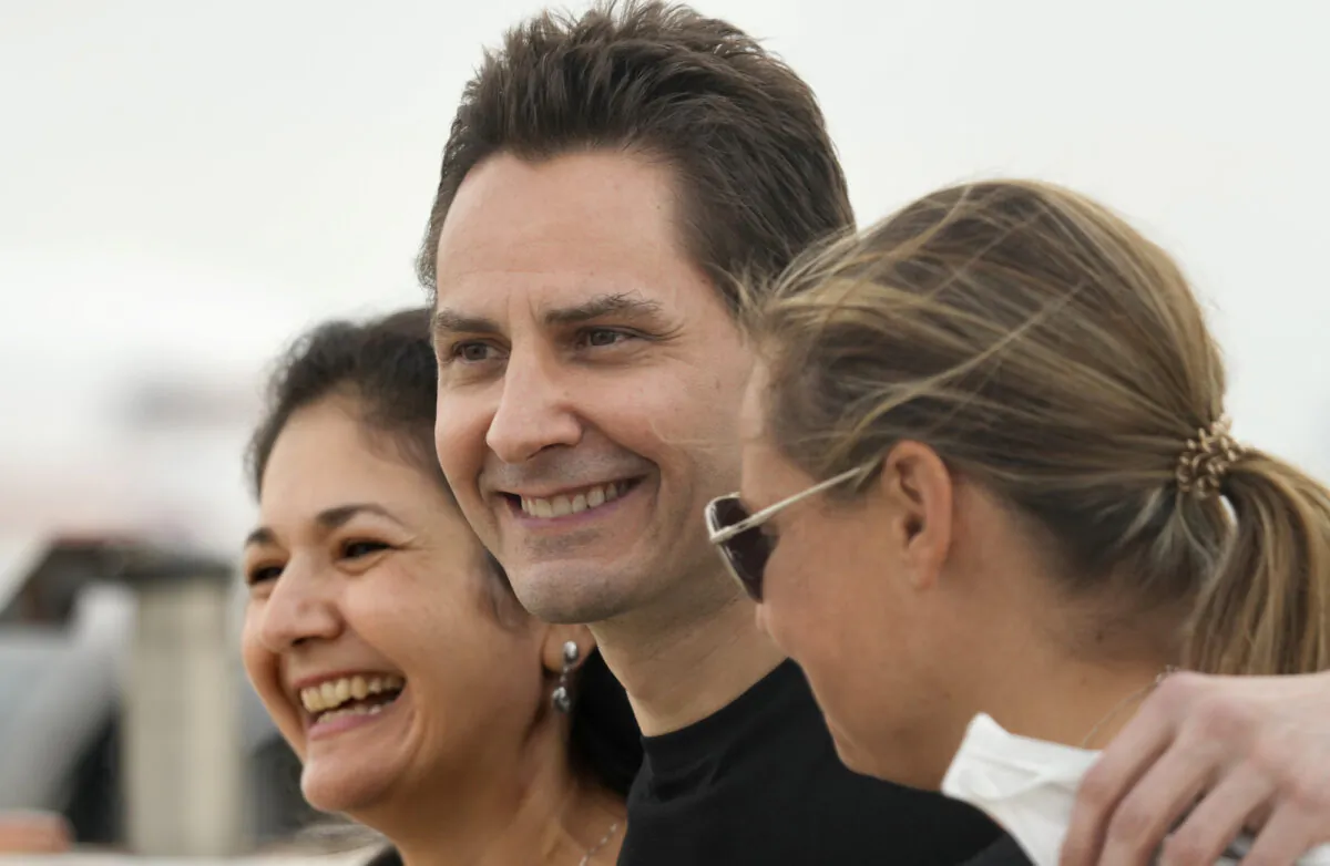 Michael Kovrig embraces his wife Vina Nadjibulla (L) and sister Ariana Botha (R) after arriving at the Pearson International Airport in Toronto on Sept. 25, 2021. (Frank Gunn/The Canadian Press via AP)