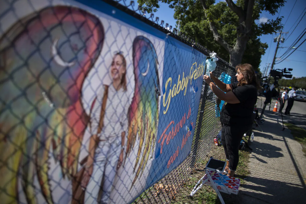 A woman places a decoration near a poster after attending the funeral home viewing of Gabby Petito at Moloney's Funeral Home in Holbrook, N.Y., on Sept. 26, 2021. (Eduardo Munoz Alvarez/AP Photo)