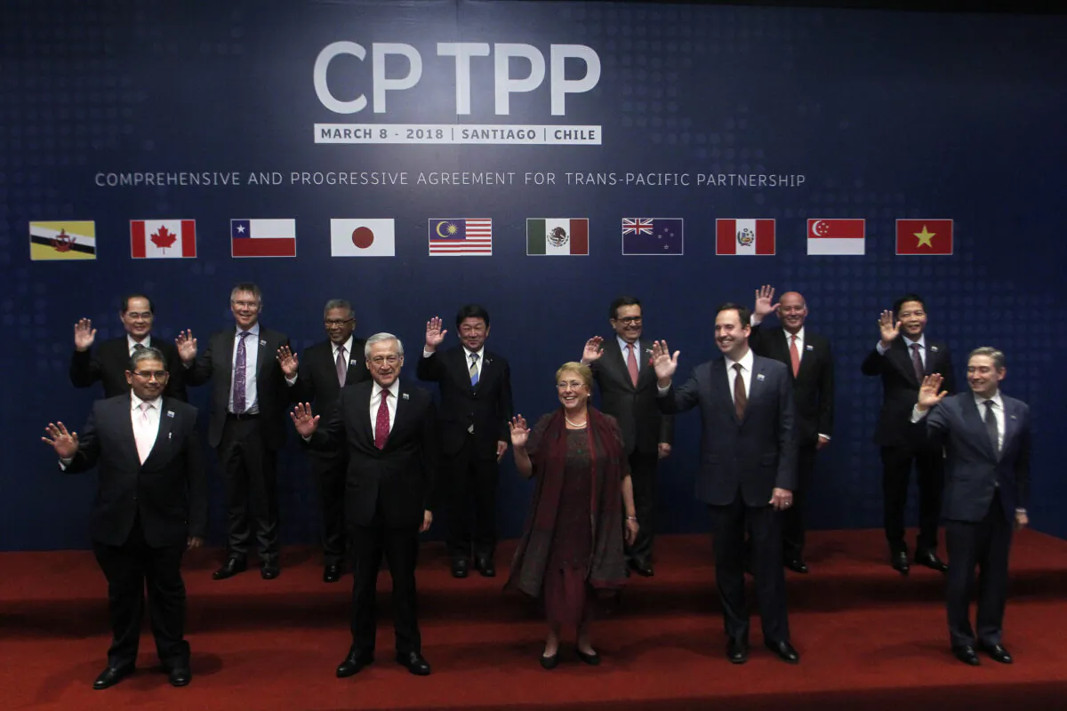 Foreign Affairs Ministers from member states wave as they pose for the official picture before signing the rebranded 11-nation Pacific trade pact, the Comprehensive and Progressive Agreement for Trans-Pacific Partnership (CPTPP), in Santiago, Chile, on March 8, 2018. (CLAUDIO REYES/AFP via Getty Images)