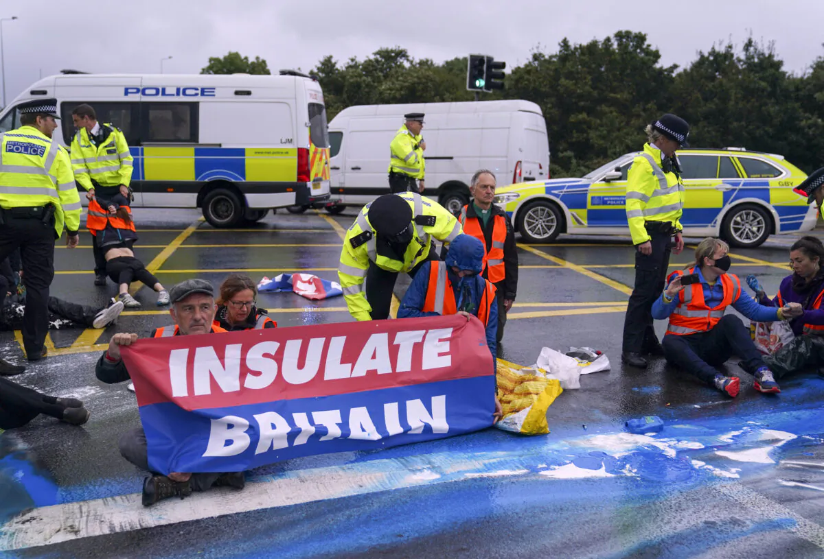 Police officers detain a protester from Insulate Britain occupying a roundabout leading from the M25 motorway to Heathrow Airport in London on Sept. 27, 2021. (Steve Parsons/PA)