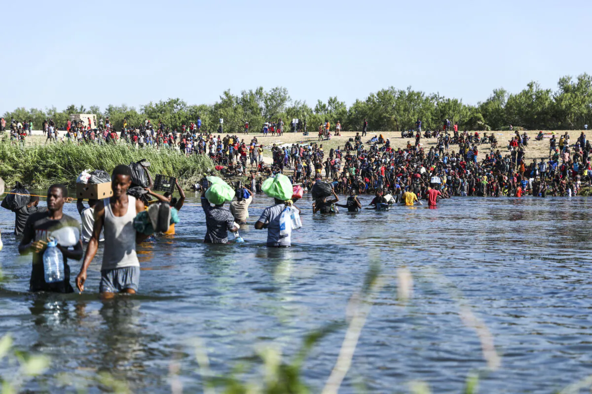Illegal immigrants take supplies back and forth between Acuña, Mexico, and the United States (far side) across the Rio Grande, the international boundary with Mexico, in Acuña, Mexico, on Sept. 20, 2021. (Charlotte Cuthbertson/The Epoch Times)