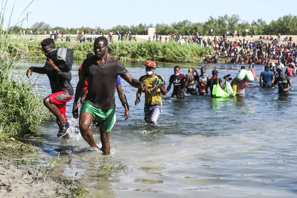 Illegal immigrants take supplies back and forth between Acuña, Mexico, and the United States (far side) across the Rio Grande, the international boundary with Mexico, in Acuña, Mexico, on Sept. 20, 2021. (Charlotte Cuthbertson/The Epoch Times)