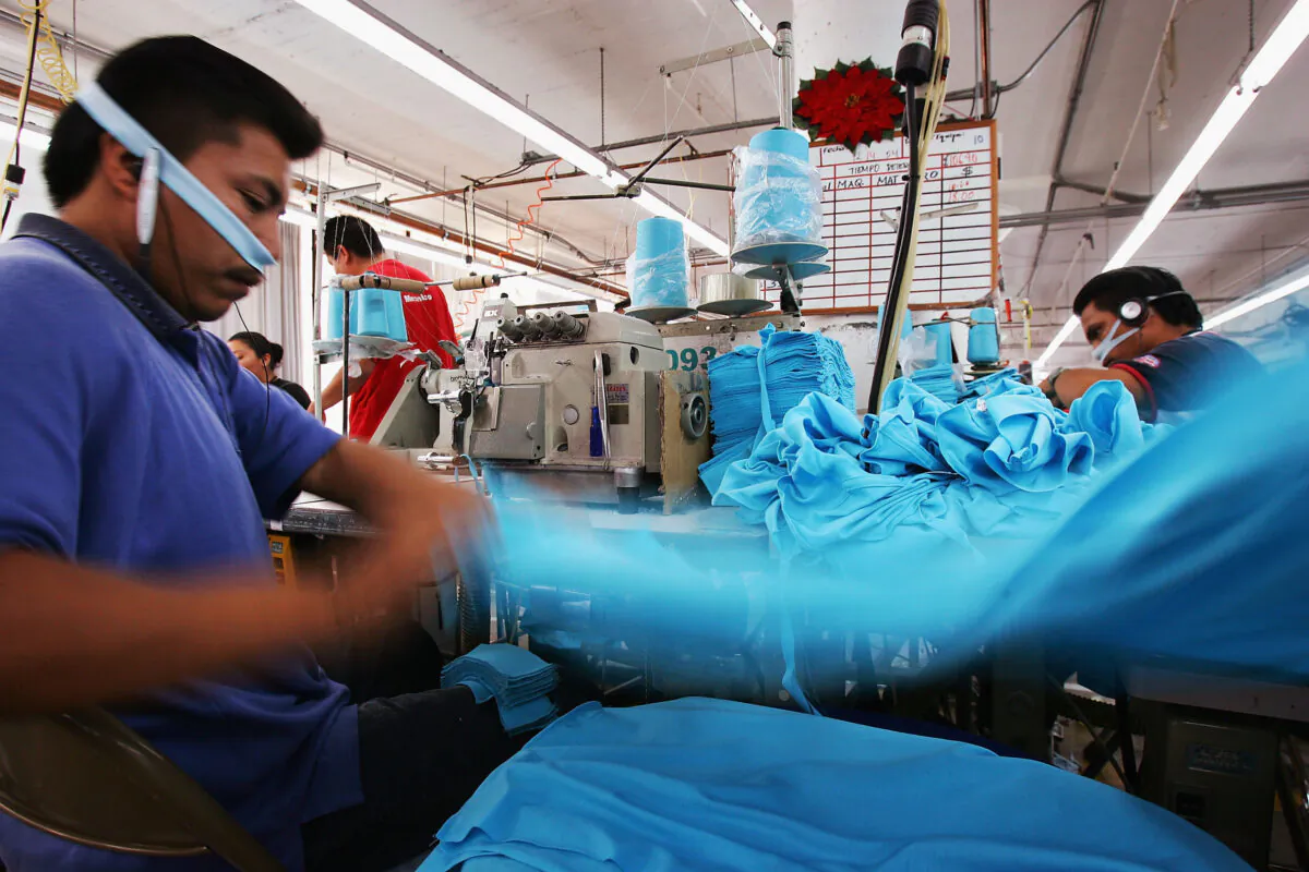 An employee tosses a garment onto a stack after sewing his portion of it at the a garment factory in Los Angeles on Dec. 14, 2004. (David McNew/Getty Images)