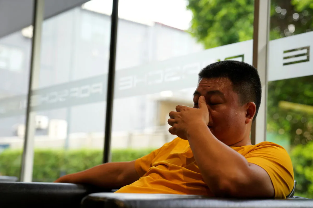 Guo Hui, whose cleaning business is owed money by China Evergrande Group, reacts as he waits at a car dealership to sell his Porsche Cayenne in order to pay his debts, in Guangzhou, Guangdong province, China on Sept. 27, 2021. (Aly Song/REUTERS)