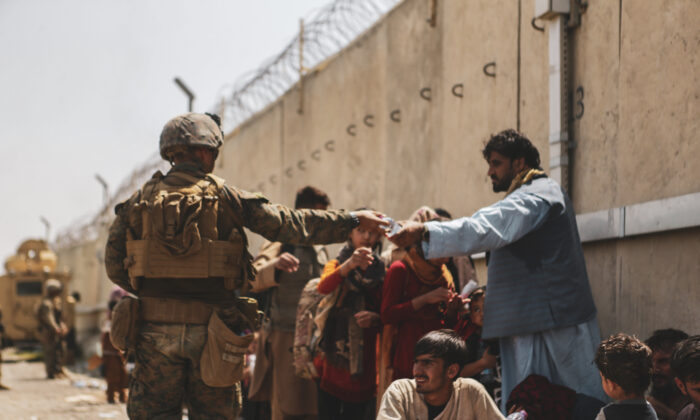 A U.S. Marine passes out water during the evacuation at Hamid Karzai International Airport  in Kabul, Afghanistan, on Aug. 21, 2021. (U.S. Marine Corps/Isaiah Campbell/Getty Images)