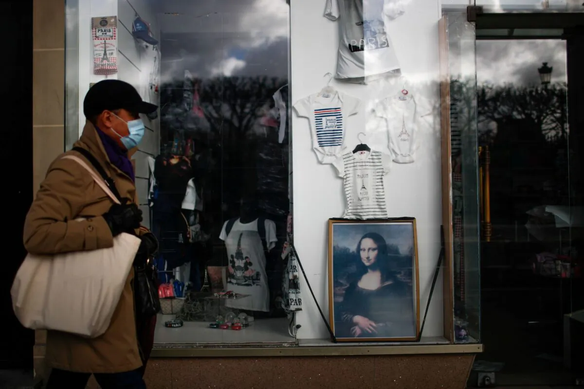 A man, wearing a protective face mask, walks past a "Mona Lisa" (La Joconde) poster displayed in a closed tourist souvenir shop at the arcades of the Rue de Rivoli in Paris amid the coronavirus disease (COVID-19) outbreak in France on Jan. 29, 2021. (Gonzalo Fuentes/Reuters)