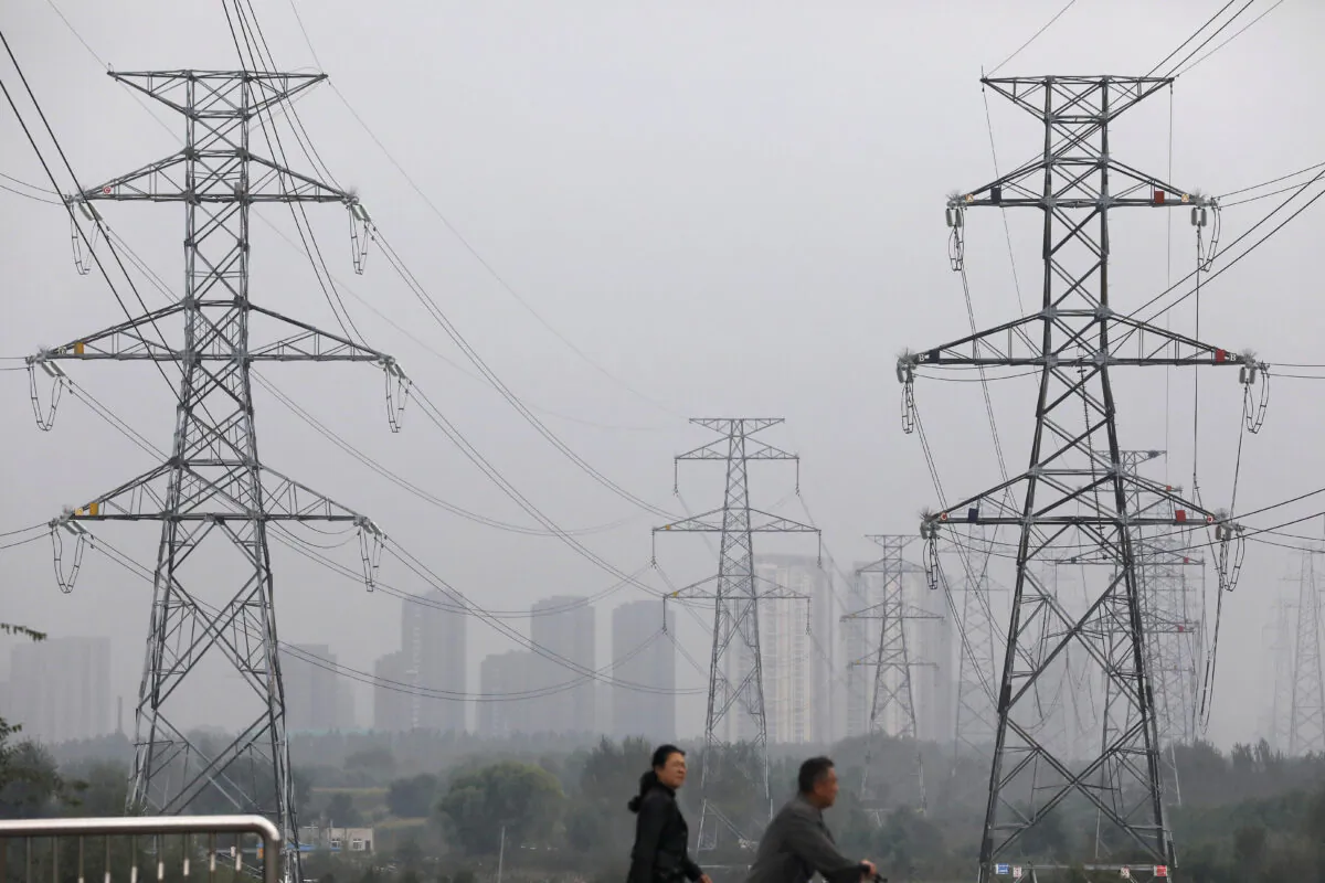 People walk past electricity pylons in Shenyang, Liaoning Province, China, on Sept. 29, 2021. (Reuters/Tingshu Wang)
