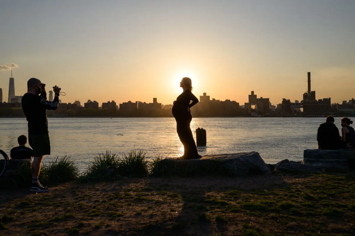 A pregnant woman poses for photos before the Manhattan city skyline at sunset in a park in Williamsburg, N.Y., on April 20, 2021. (Ed Jones/AFP via Getty Images)