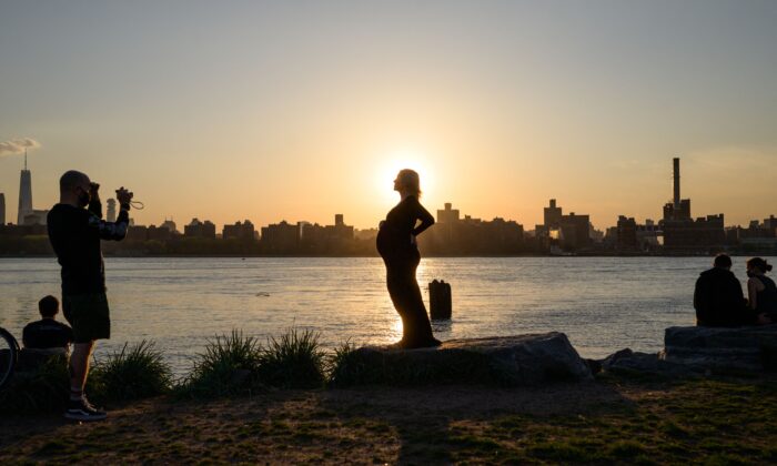A pregnant woman poses for photos before the Manhattan city skyline at sunset in a park in Williamsburg, N.Y., on April 20, 2021. (Ed Jones/AFP via Getty Images)