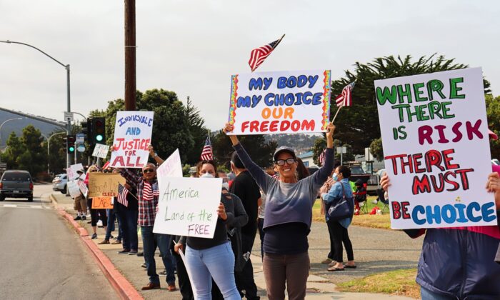 People hold signs calling for freedom of choice during a rally protesting vaccine mandates in Monterey, Calif., on Sept. 26, 2021. (Cynthia Cai/The Epoch Times)