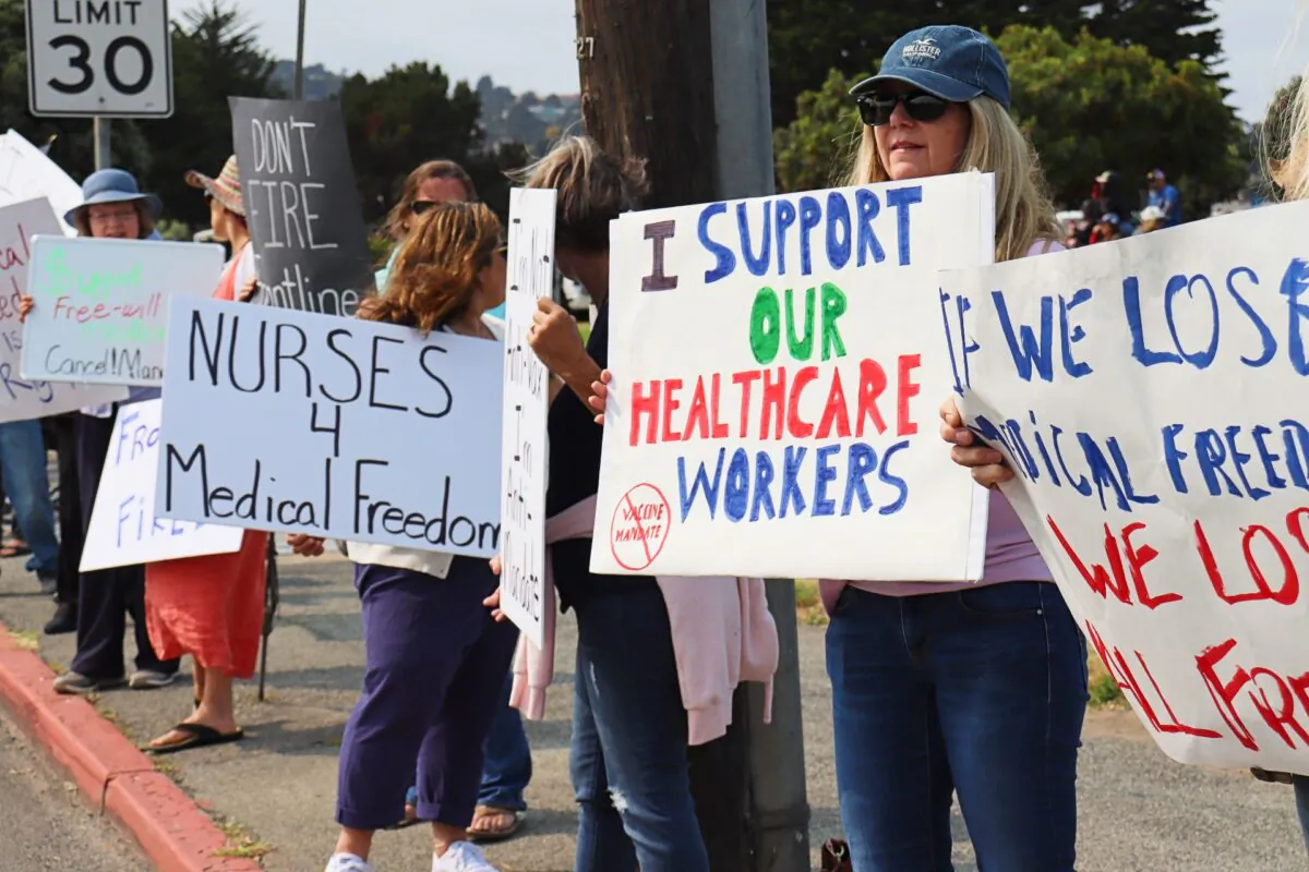 People hold signs supporting health care workers during a rally opposing vaccine mandates in Monterey, Calif., on Sept. 26, 2021. (Cynthia Cai/The Epoch Times)