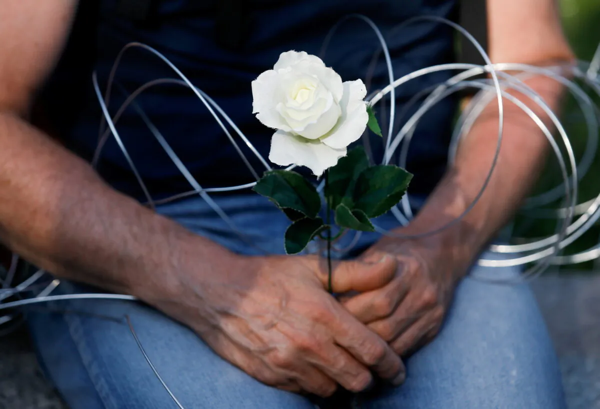 A person holds a flower and wire during a protest against the state of emergency declared at the Polish border with Belarus, in front of the Parliament in Warsaw, Poland, on Sept. 6, 2021. (Kacper Pempel/Reuters)