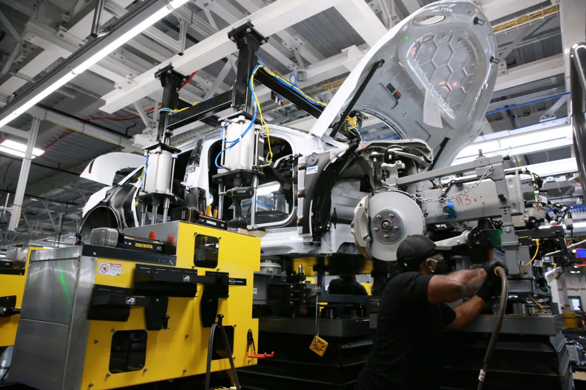 Martwaine Robinson works to marry the body structure with the battery pack and the front and rear sub frames as he and fellow workers assemble electric vehicles at the Lucid Motors plant in Casa Grande, Ariz., on Sept. 28, 2021. (Caitlin O'Hara/Reuters)