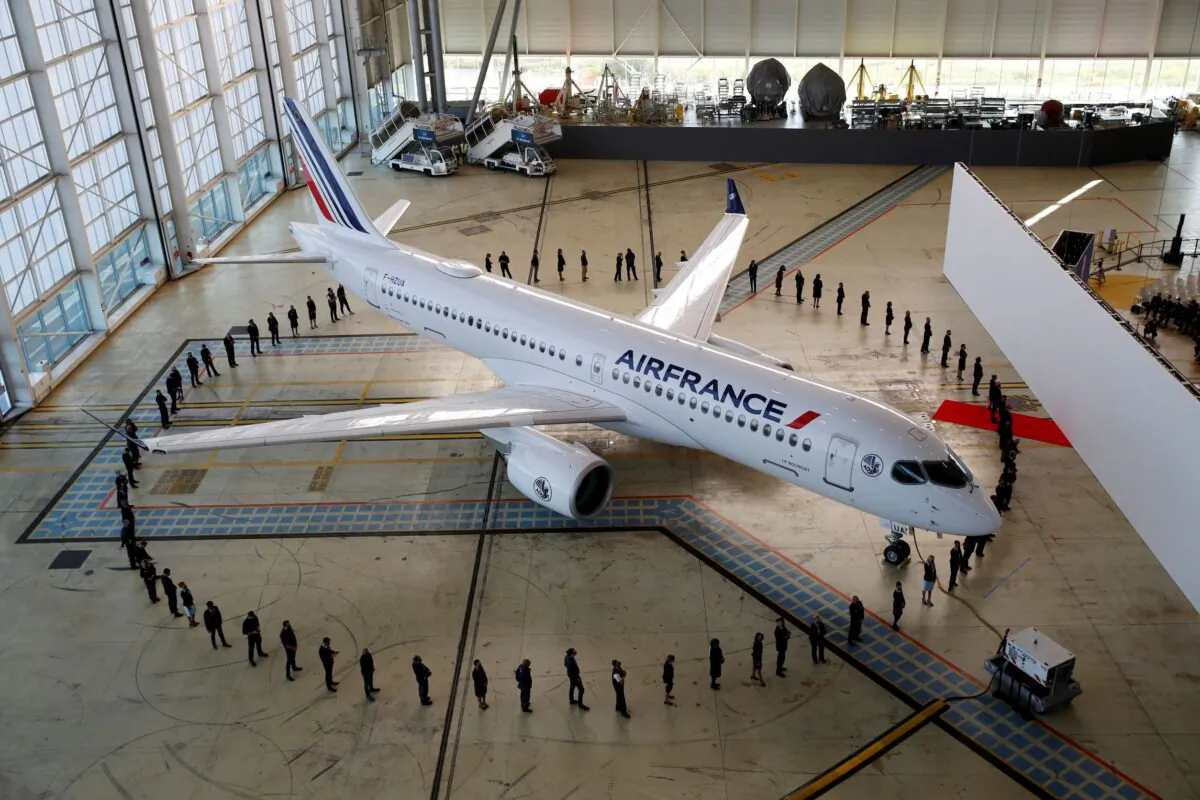 Air France employees stand around the first Air France airliner's Airbus A220 during a ceremony in the Air France hangar at Paris Charles de Gaulle airport in Roissy near Paris, France, on Sept. 29, 2021. (Gonzalo Fuentes/Reuters)
