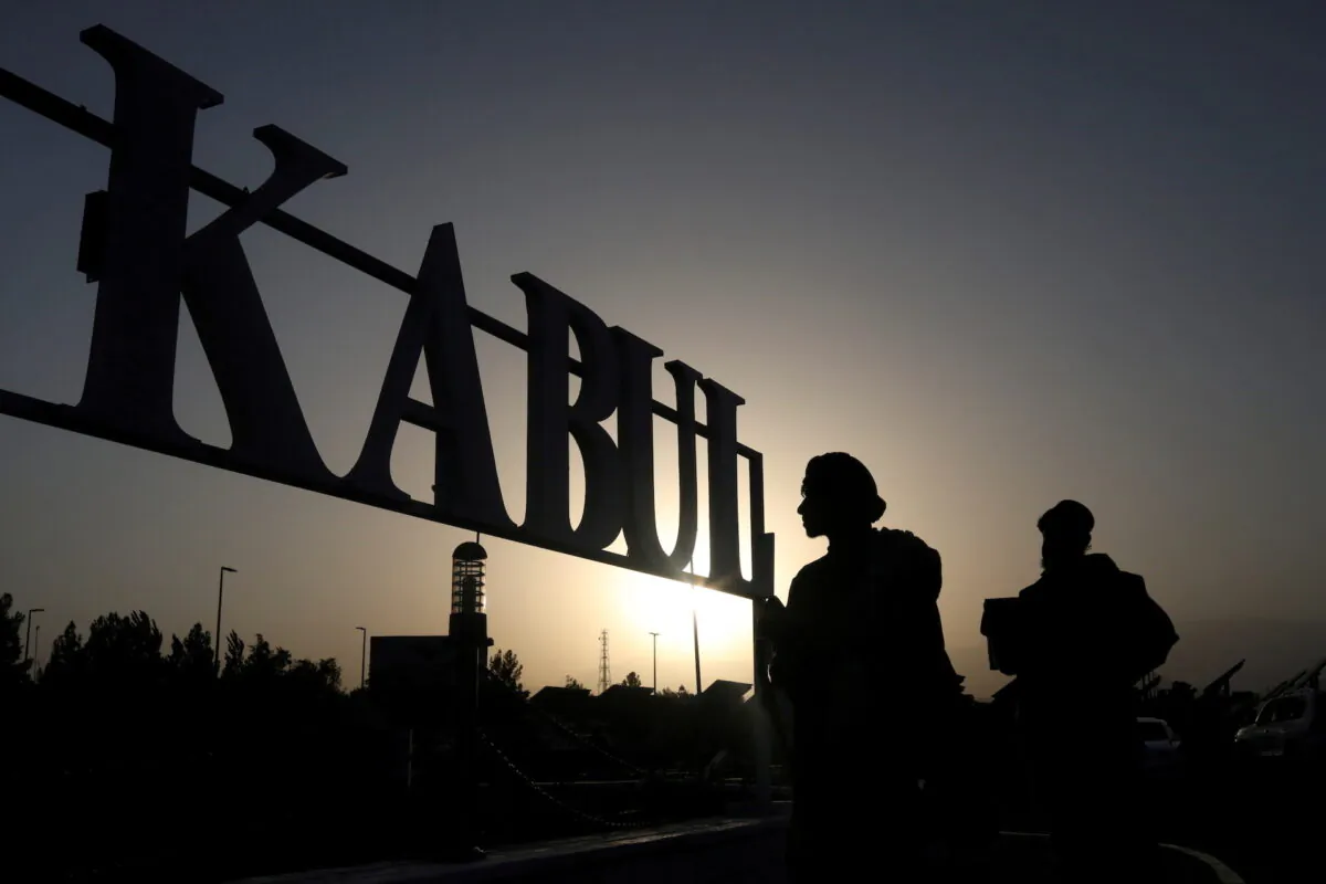 Taliban terrorists stand in front of a sign at the international airport in Kabul, Afghanistan, on Sept. 9, 2021. (West Asia News Agency/Reuters)