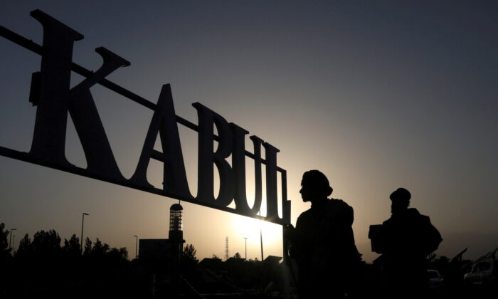 Taliban terrorists stand in front of a sign at the international airport in Kabul, Afghanistan, on Sept. 9, 2021. (West Asia News Agency/Reuters)