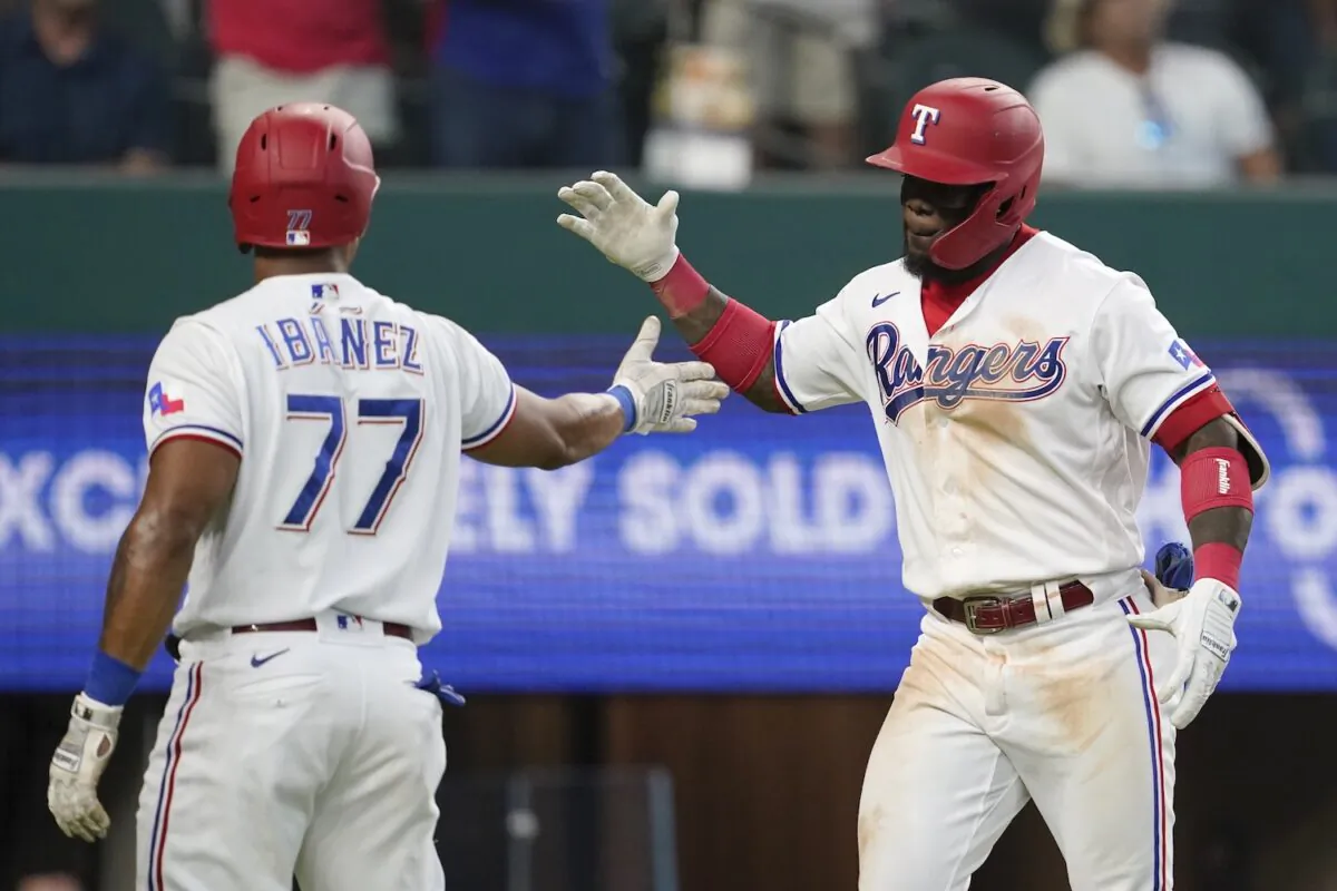 Texas Rangers' Andy Ibanez (77) and Adolis Garcia, right, celebrate a two-run home run by Garcia that also scored Ibanea in the fifth inning of a baseball game against the Los Angeles Angels in Arlington, Texas on Sept. 30, 2021. (AP Photo/Tony Gutierrez)