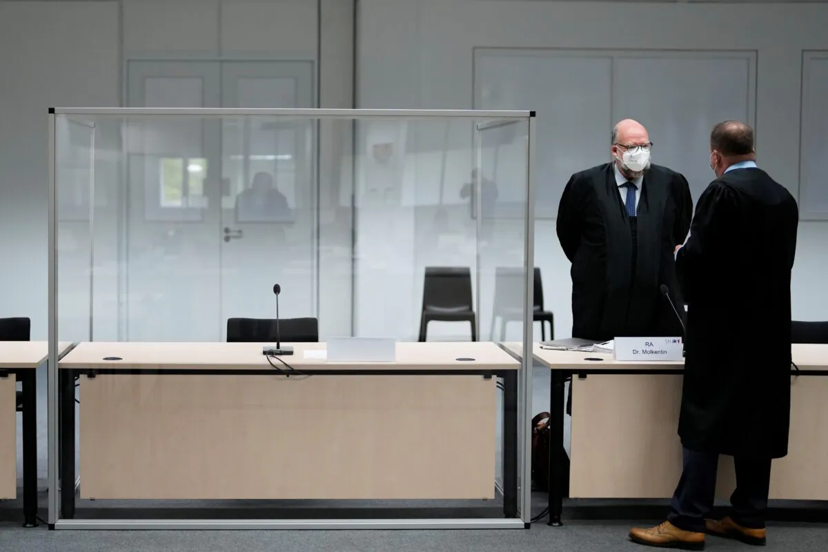 Two lawmakers stand next to the empty seat of the accused 96-year-old former secretary to the SS commander of the Stutthof concentration camp, at the Landgericht Itzehoe court, before a trial against her, in Itzehoe, Germany, on Sept. 30, 2021. (Markus Schreiber/Pool via Reuters)